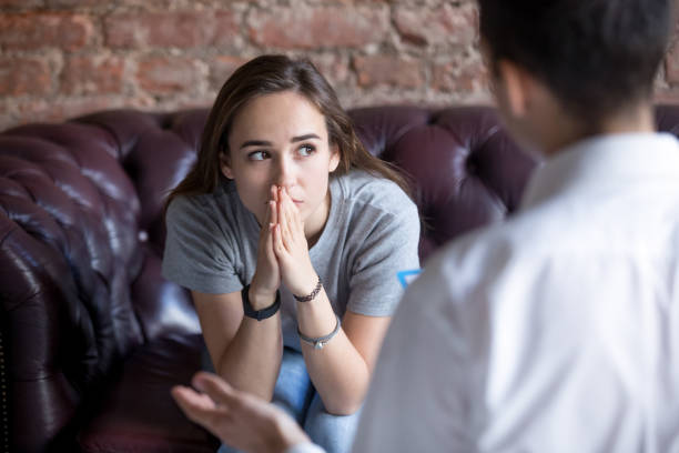 Unhappy young girl at the psychologist Young woman visiting therapist counselor. Girl feeling depressed, unhappy and hopeless, needs assistance. Serious disease, unwilling pregnancy, abort or death of loved one, addiction to drugs concept counselling session stock pictures, royalty-free photos & images