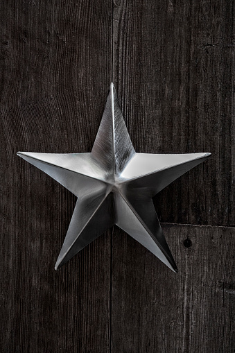 This is a photograph of a metal silver shaped star on an old retro wood background