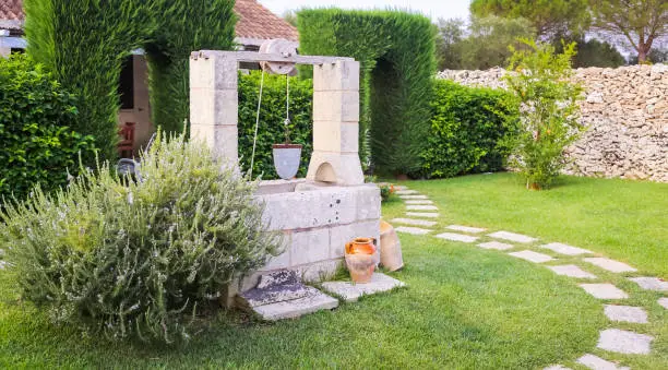Summer season in Italy. Desing water well in an elegant garden.