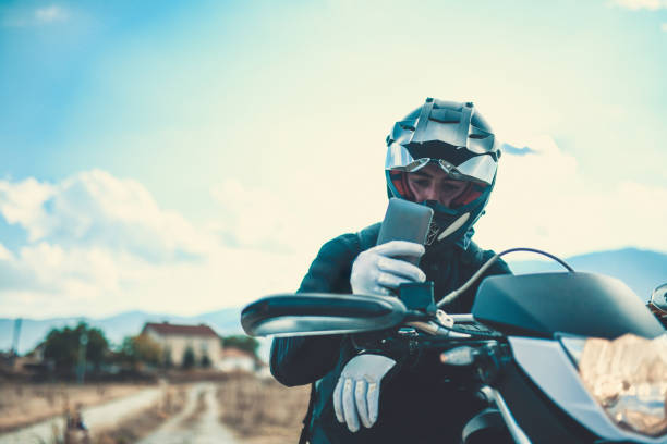 Motorcyclist Adjusting the Navigation on Mobile Phone on Lake Side Motorcyclist Adjusting the Navigation on Mobile Phone on Lake Side motorcycle biker stock pictures, royalty-free photos & images