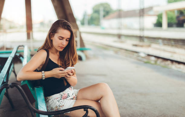 istock Woman using phone at the train station 1036321922