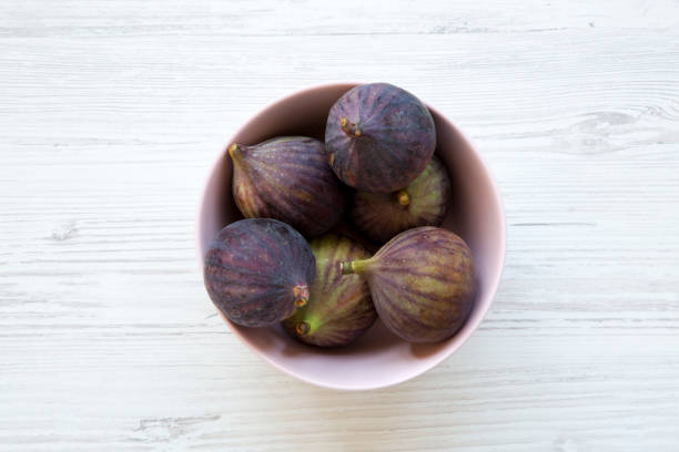 istock Fresh figs in a pink bowl on a white wooden table. Top view, overhead, from above. 1036322644