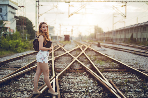 Young woman walking across railroad tracks