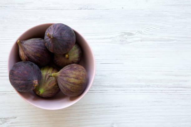 istock Fresh figs in a pink bowl on a white wooden table. Top view, overhead, from above. Copy space. 1036322668