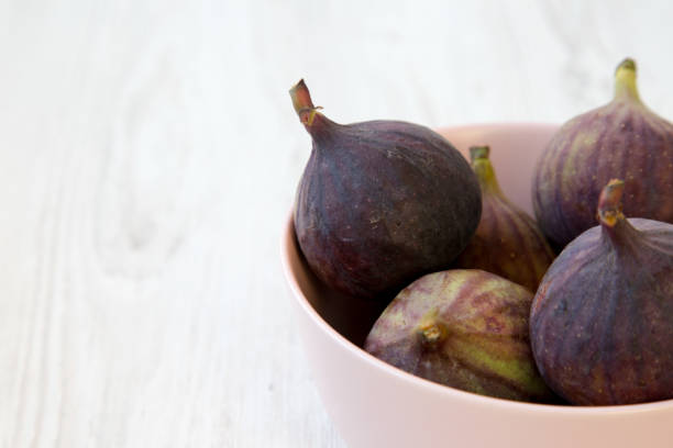 istock Fresh figs in a pink bowl on a white wooden background, side view. Copy space. 1036322922