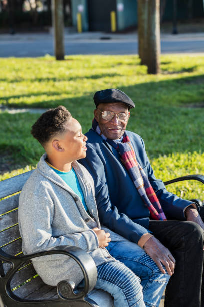 african-american boy mit seinem urgroßvater auf bank - great grandson stock-fotos und bilder