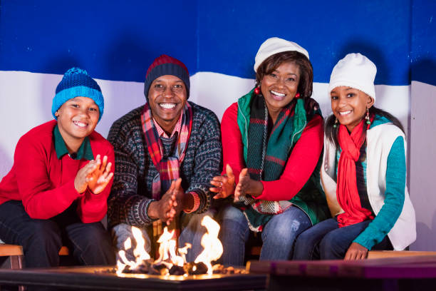 famille afro-américaine rester chaud autour de feu de camp - rubbing human hand togetherness women photos et images de collection