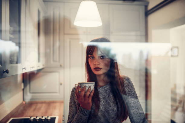 istock Cute Female in Kitchen Drinking Coffee and Looking through Window 1036333528