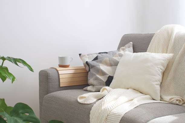 casa interior vivendo aconchegante sala sofá almofada caneca de café de malha xadrez monstera planta estilo escandinavo de quarto decoração espaço cópia - cushion - fotografias e filmes do acervo