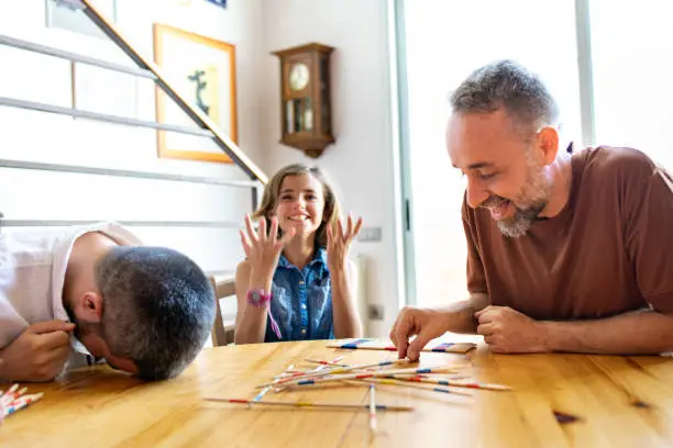 Gay parents playing Pick Up Sticks with their kids