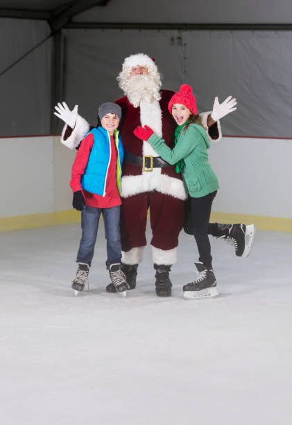 dos niños, hermanos, con santa en pista de patinaje de hielo - santa claus waving christmas photography fotografías e imágenes de stock