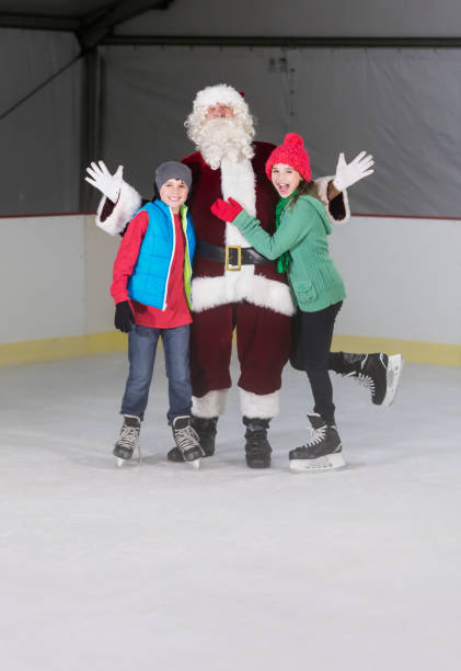 due bambini, fratelli, con babbo natale alla pista di pattinaggio su ghiaccio - santa claus waving christmas photography foto e immagini stock