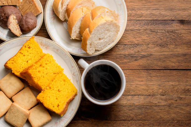 frühstück essen auf einem holztisch, karottenkuchen, brot, kekse und einen heißen kaffee mit dampf aus - frühstück fotos stock-fotos und bilder