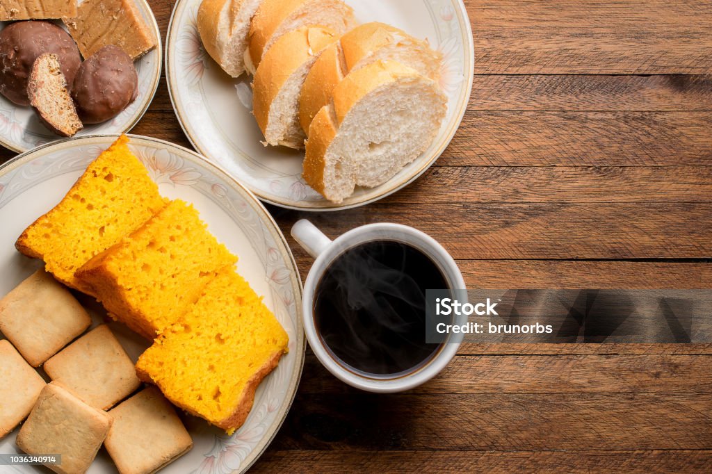 Aliments du petit déjeuner sur une table en bois, gâteau aux carottes, pain, biscuits et un café chaud avec de la vapeur qui sort - Photo de Petit déjeuner libre de droits