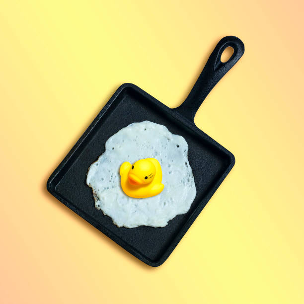 istock Cast-iron frying pan with fried eggs, toy duckling instead of yolk 1036344218