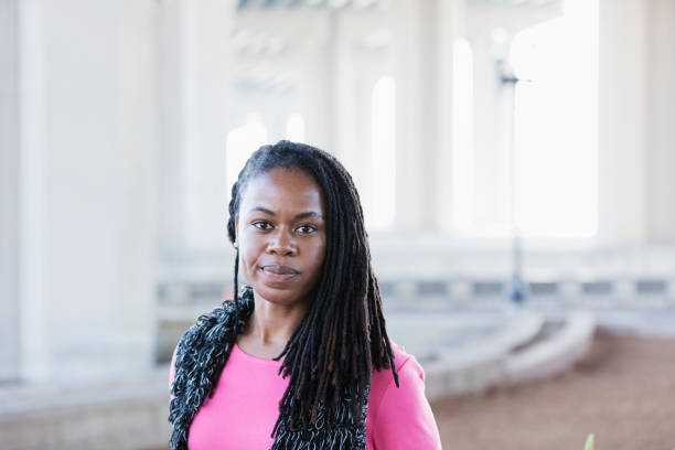 Mid adult African-American woman with cornrow braids An African-American mid adult woman in her 30s standing outdoors, looking at the camera with a serious expression on her face. black hair braiding stock pictures, royalty-free photos & images