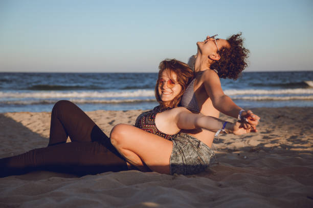 Two women in love hugging and sitting by the sea