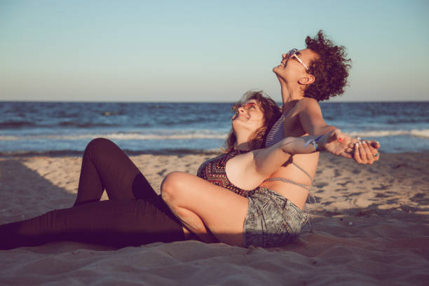 Two women in love hugging and sitting by the sea