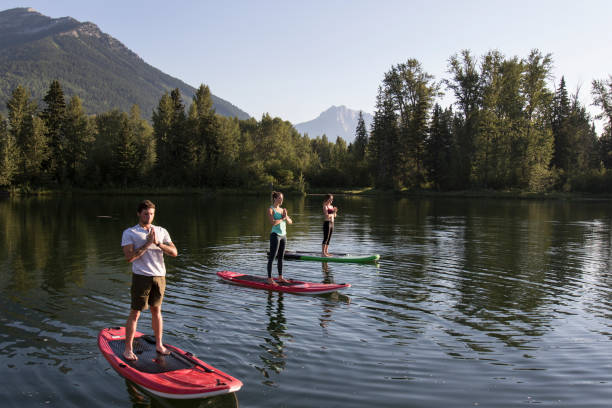 paddle board yoga - vacations women men stability imagens e fotografias de stock