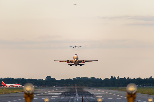GATWICK AIRPORT, ENGLAND, UK – SEPTEMBER 13 2018: View directly down the runway as an easyJet Airlines plane takes off from Gatwick Airport with planes coming in to land behind it in the background.