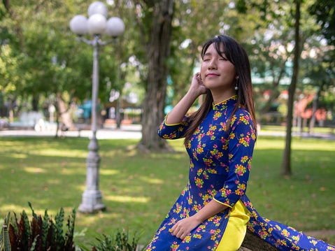 Young woman in Ao Dai deep breathing in public park