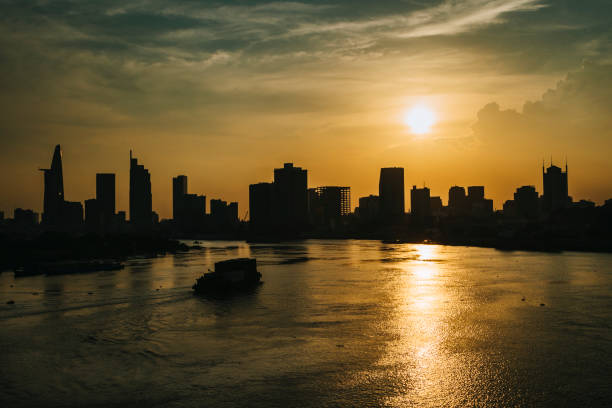 Silhouette of Ho Chi Minh City, Saigon at sunset with a cargo ship approaching
