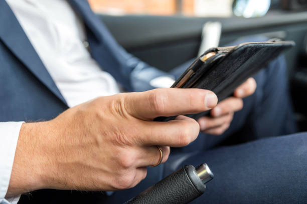 istock Businessman working on tablet and smartphone inside car on bright day 1036435162