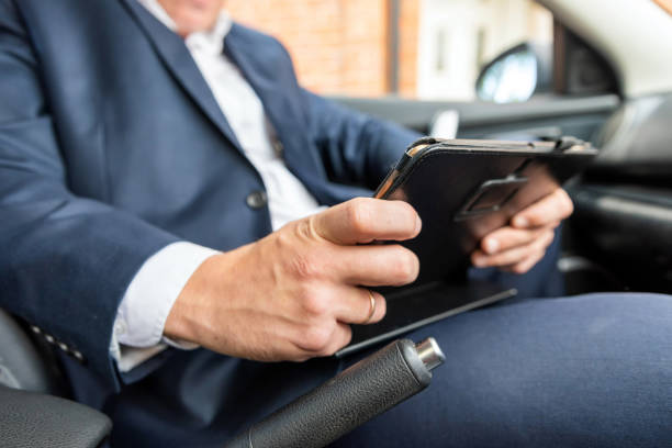istock Businessman working on tablet and smartphone inside car on bright day 1036435178