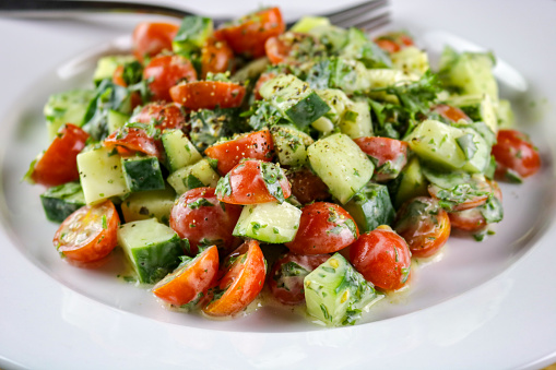 A freshly made cucumber, tomato and herb salad with a creamy vinaigrette dressing