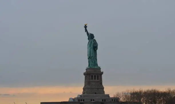 View of the sunset from the New York harbor, with Lady Liberty in front row.