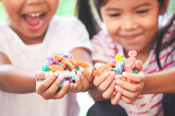 Two asian child girls holding sweet candies in thier hands and share to each other