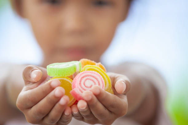 cute asian child girl holding jelly candies in hand and sharing to other - eye catcher imagens e fotografias de stock