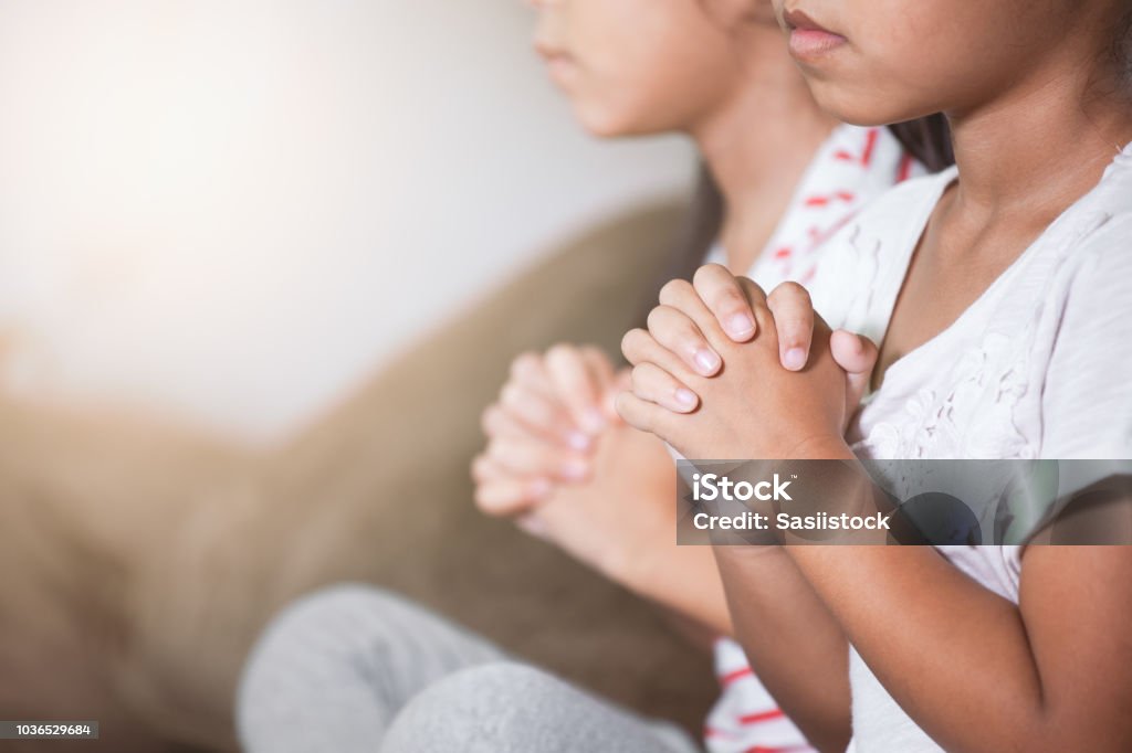 Cute asian child girl and her sister praying with folded her hand in the room together Cute asian child girl and her sister praying with folded her hand in the room together for faith,spirituality and religion concept Child Stock Photo