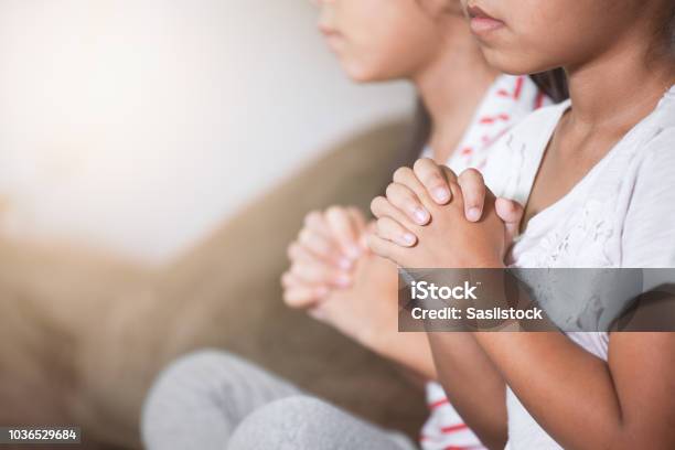 Cute Asian Child Girl And Her Sister Praying With Folded Her Hand In The Room Together Stock Photo - Download Image Now
