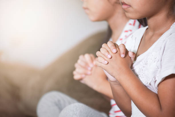 cute asian child girl and her sister praying with folded her hand in the room together - praying girl imagens e fotografias de stock