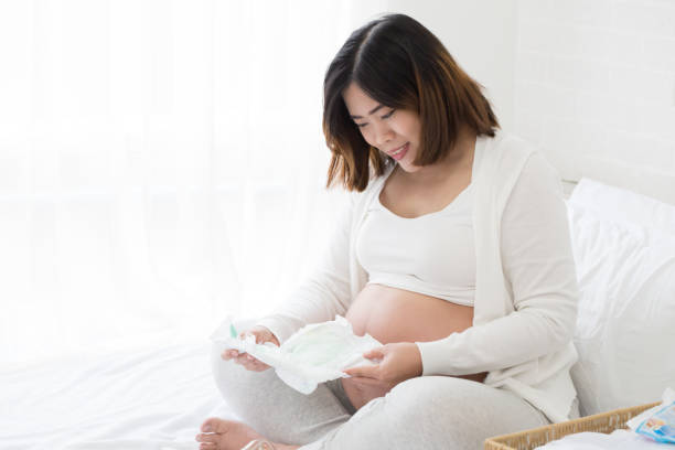 妊娠中の女性は、新生児用おむつを準備します。 - diaper shopping human pregnancy supermarket ストックフォトと画像