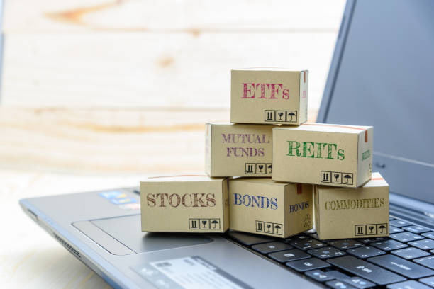 Personal portfolio and online wealth management with risk diversification concept : Paper boxes of financial instruments i.e ETFs, REITs, stocks, bonds, mutual funds and commodities, all on a laptop.