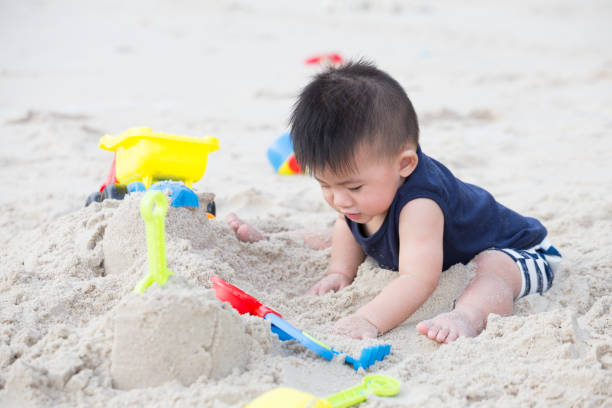 istock Baby boy playing with sand on tropical beach 1036563220