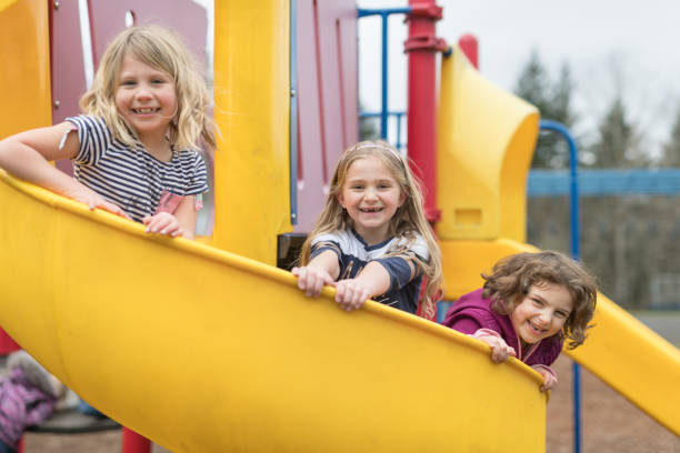 istock Three 1st grade girls pose on the playground slide 1036563304