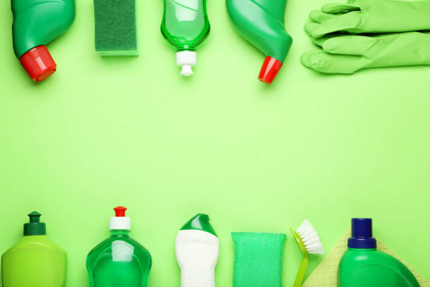 istock Bottles with detergent and cleaning tools on green background 1036578126