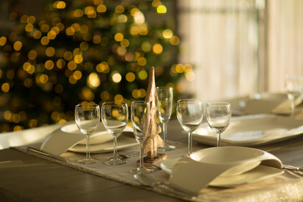 empty glasses on covered table in dining room with blurred christmas tree in background