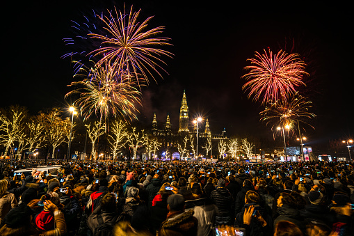 many people, locals and tourists, celebrating new years eve together with beautiful fireworks over city hall of Vienna