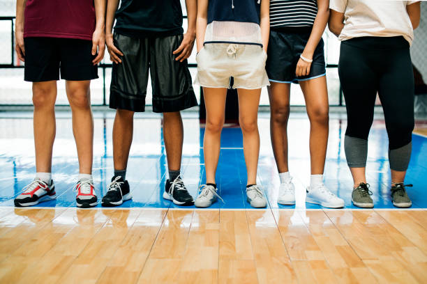 gruppo di giovani amici adolescenti su un campo da basket in piedi di fila - hanging basket foto e immagini stock