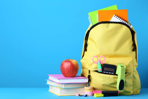 istock Yellow backpack with school supplies on blue background 1036600376