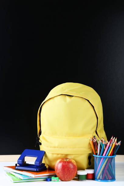 istock Yellow backpack with school supplies on black background 1036600500