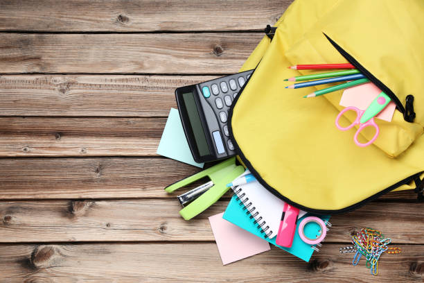 istock Yellow backpack with school supplies on brown wooden table 1036600718