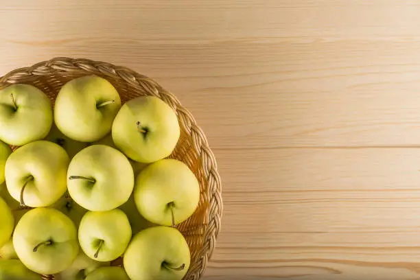 Basket with green apples on wooden background, top view
