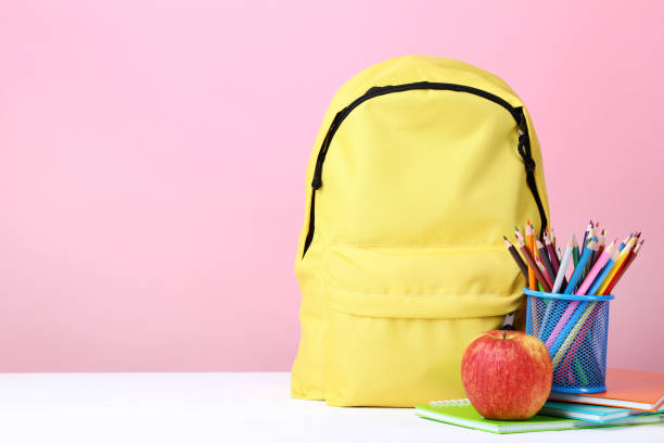 istock Yellow backpack with school supplies on pink background 1036603938