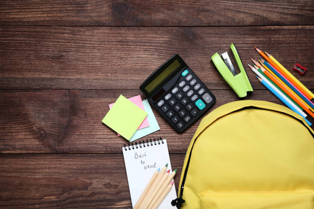 istock Yellow backpack with school supplies on brown wooden table 1036606334