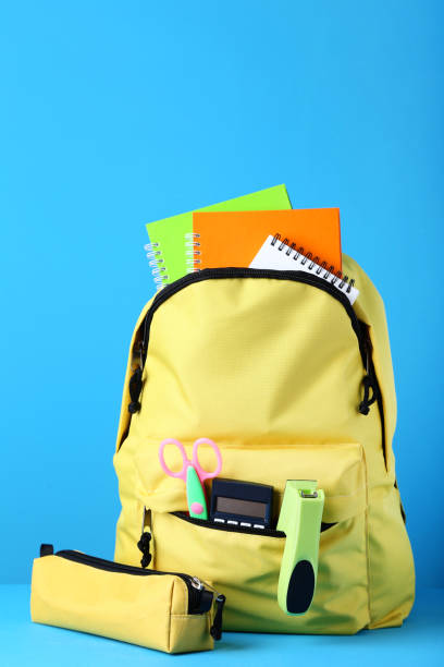 istock Yellow backpack with school supplies on blue background 1036606446